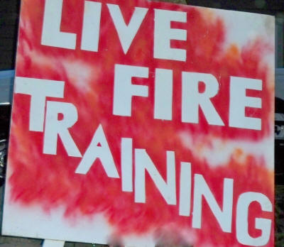 A sign reading "LIVE FIRE TRAINING" with a red and white flame-like background.