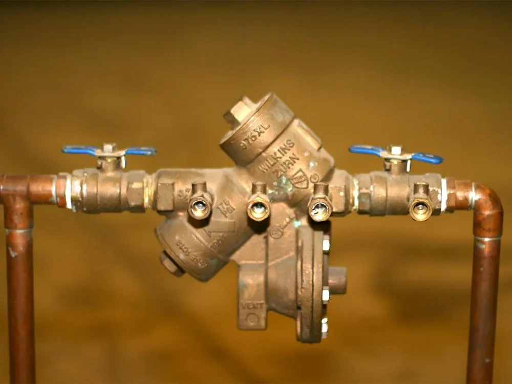 Copper piping with a backflow prevention device and blue-handled shutoff valves.