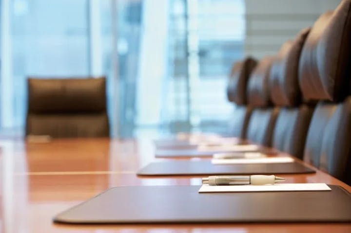 Boardroom table with chairs, notepads, and pens, indicating a professional meeting environment.