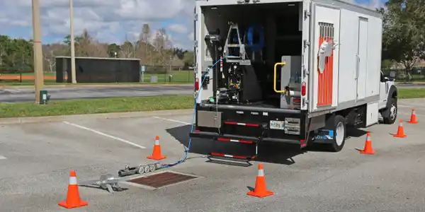 A mobile friction tester on a runway with a truck and cones.