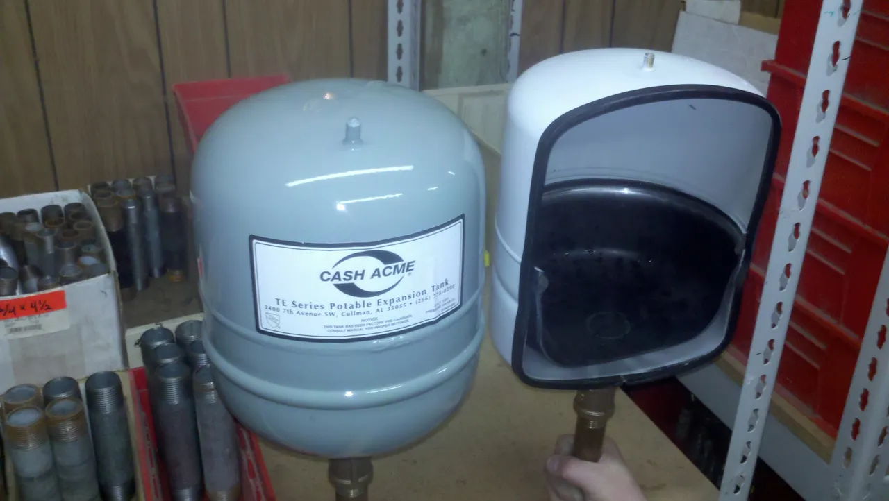 A water expansion tank and an open, wall-mounted mailbox shown side by side in a store or storage area.
