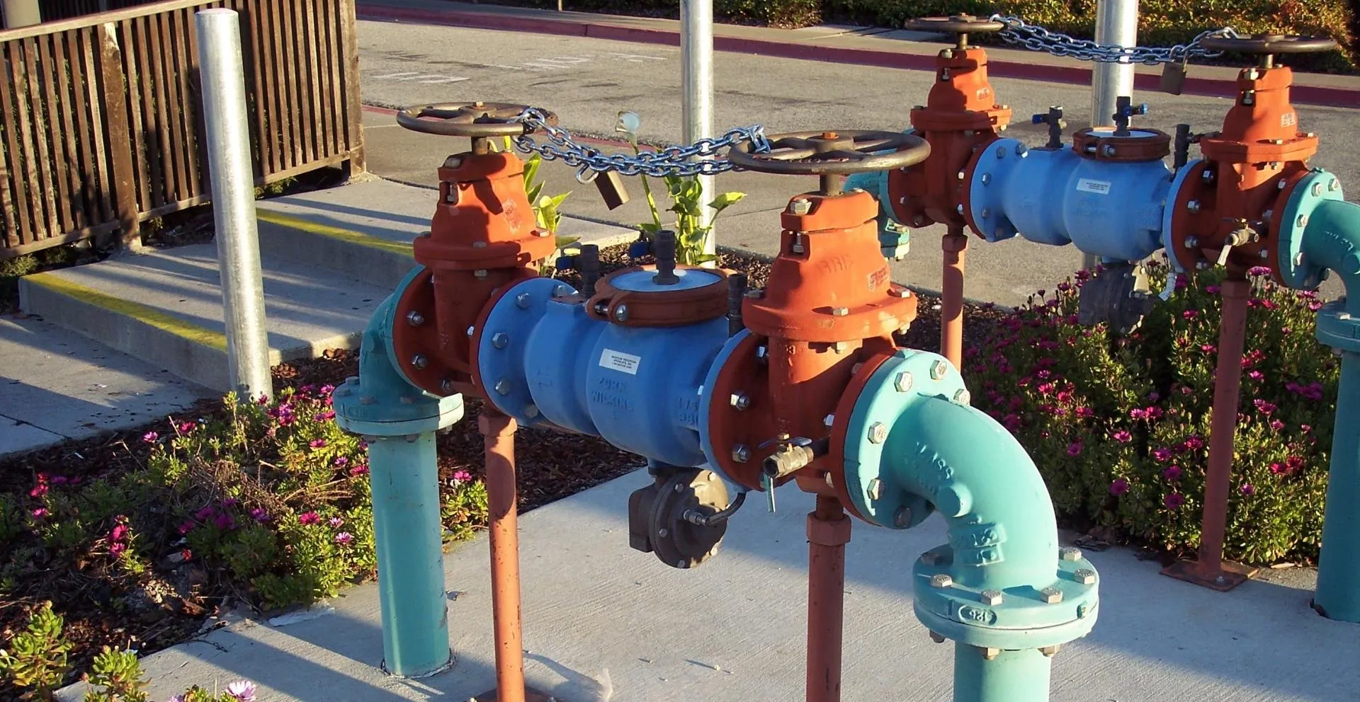 Industrial water piping system with valves and colorful pipes above ground.