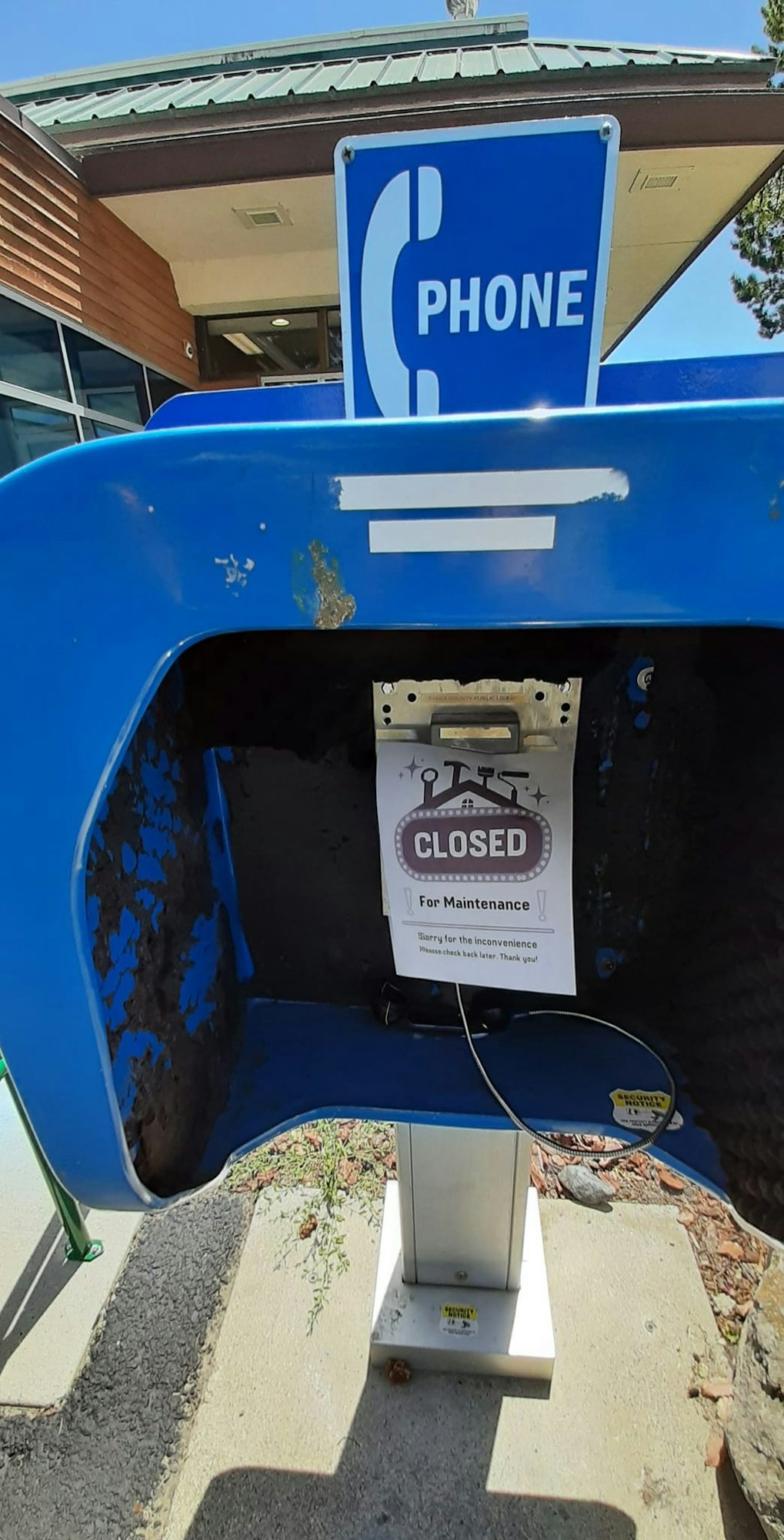 An empty phone booth with a "CLOSED for Maintenance" sign.