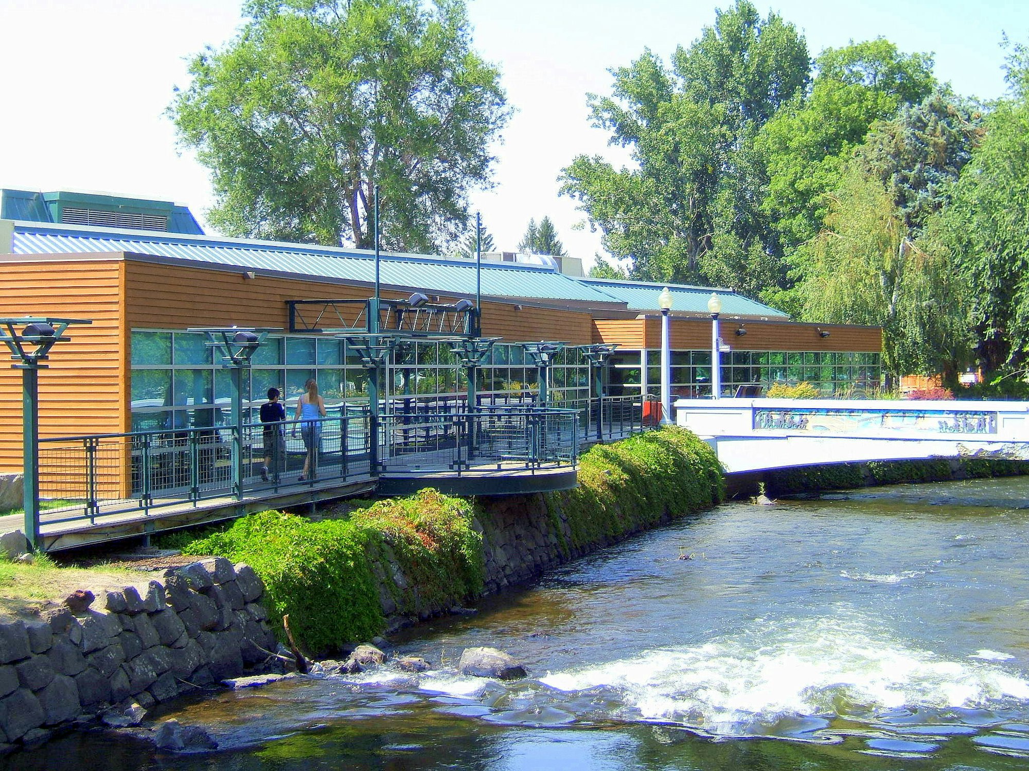 Main branch of Baker County Library District on riverside waterfront with footbridge to city park