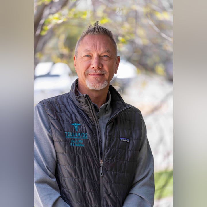 A person wearing a "Telluride Regional Medical Center" vest, standing outdoors with a blurred background.