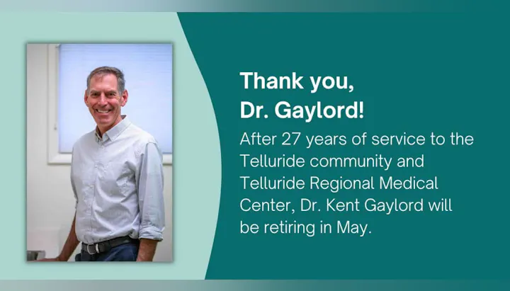 A man smiling next to a retirement announcement for Dr. Kent Gaylord after 27 years of service in Telluride.