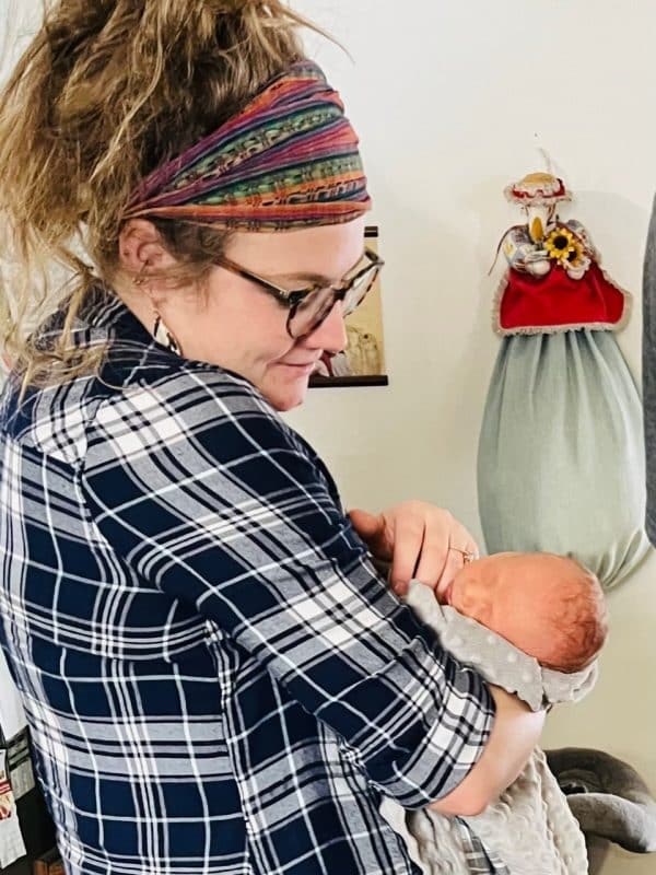 A person holding a swaddled baby, looking at them affectionately.
