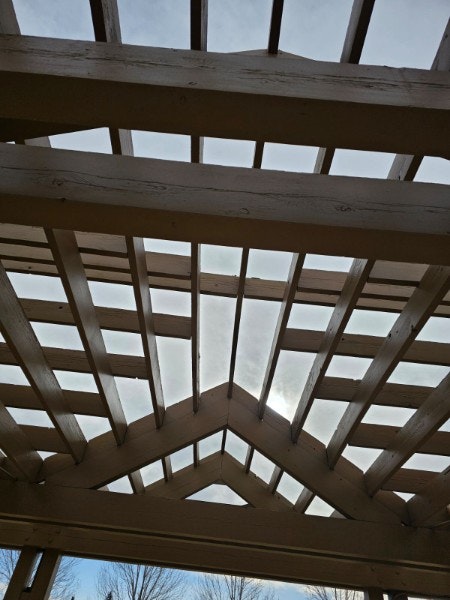 Wooden roof frame under construction against a cloudy sky.