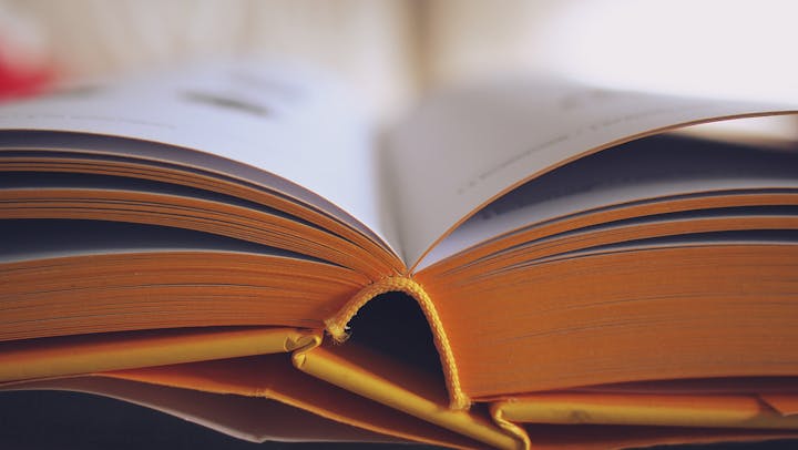 An open book with visible text and a bookmark on a bright background.