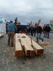 People working with large wooden beams at an outdoor event or construction site.