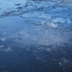 A partially frozen body of water with patches of ice and open water.