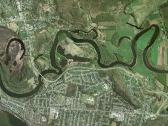 Aerial view of a winding river passing through a landscape with urban and rural areas.