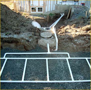 Septic system installation with a tank, pipes, and drainage field in a construction site setting.