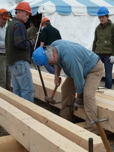 People wearing hard hats working on wooden beams at a construction site.