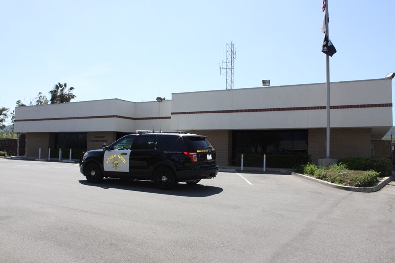A police SUV parked in front of a building with palm trees and a clear sky.