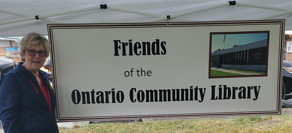 A person next to a sign: "Friends of the Ontario Community Library."