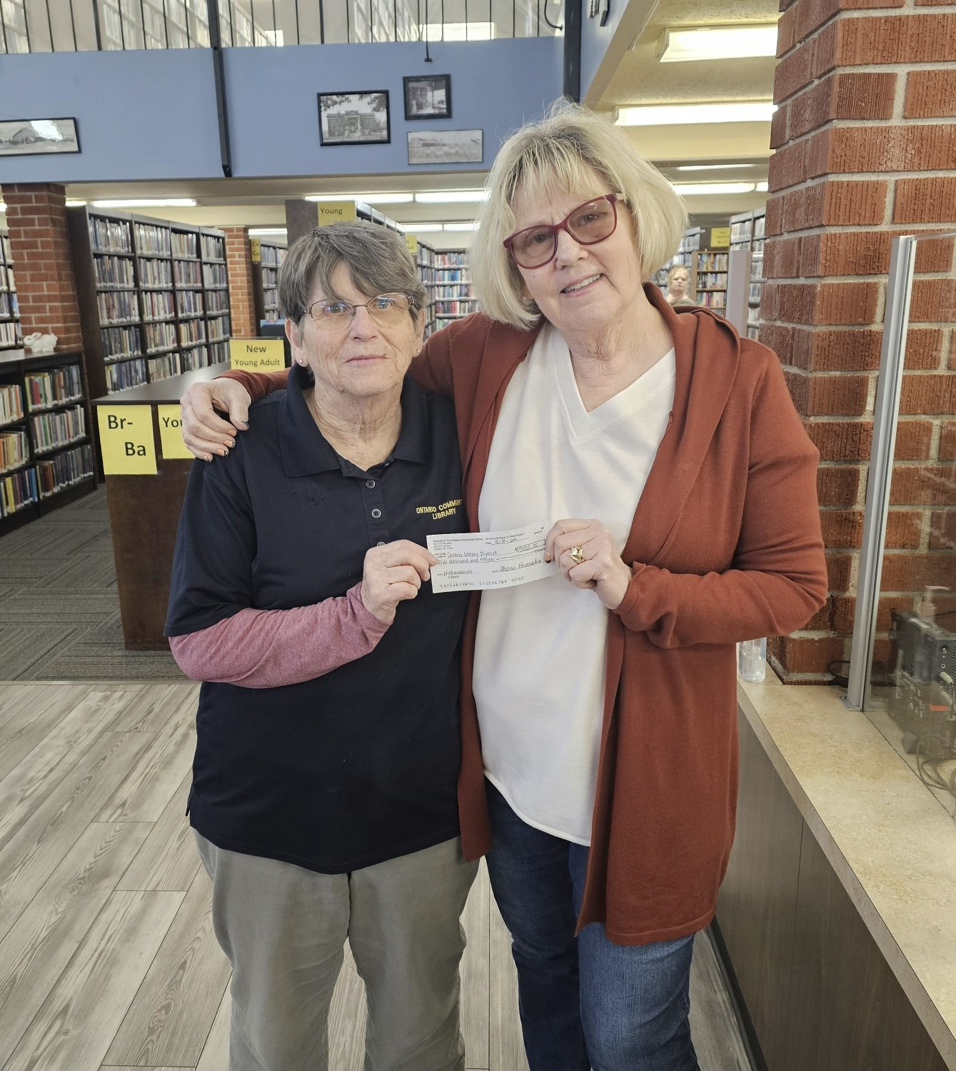 Two women holding a check in a library.