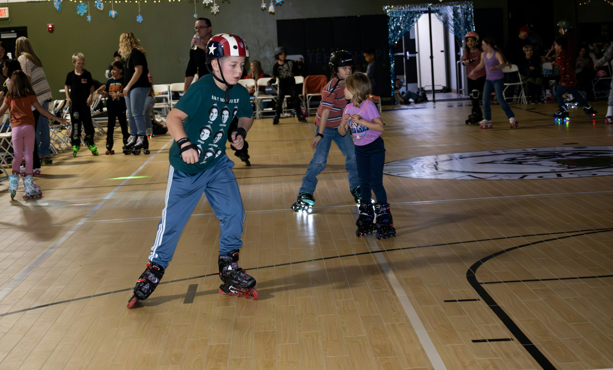 A group of kids roller skating in a lively indoor setting, with some wearing colorful helmets and fun outfits.