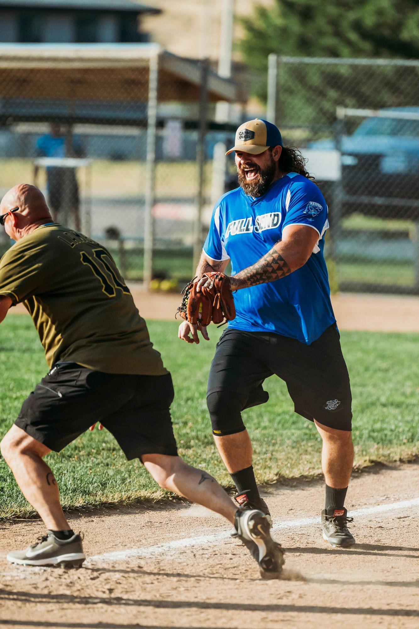 A softball game in action with a player about to catch a ball and another running to base.