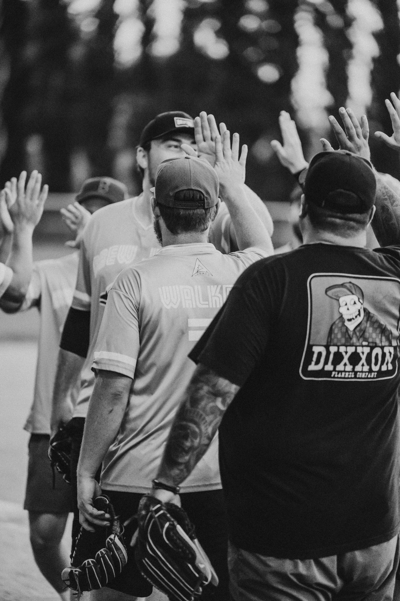 A group of people giving high-fives, likely teammates celebrating during a sports event, captured in black and white.