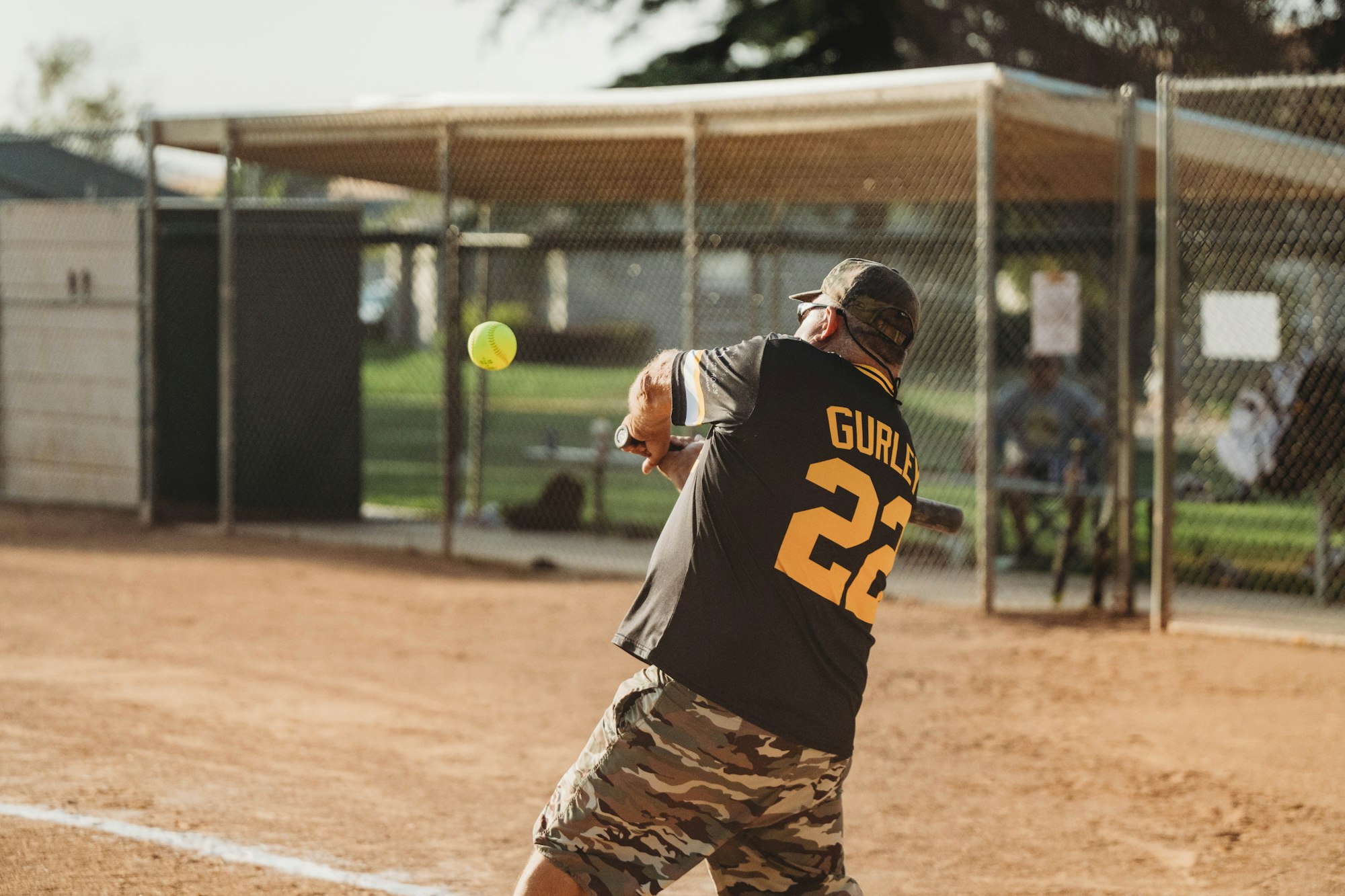 A player swinging at a softball on a dusty field.