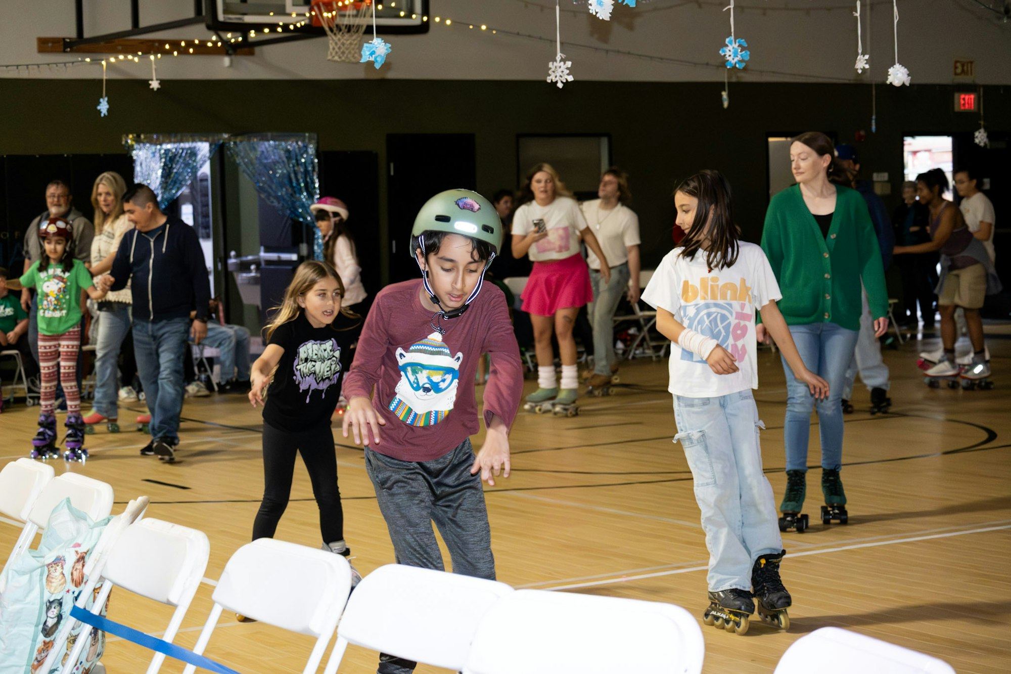 A lively indoor roller skating event with kids and adults enjoying skating together.