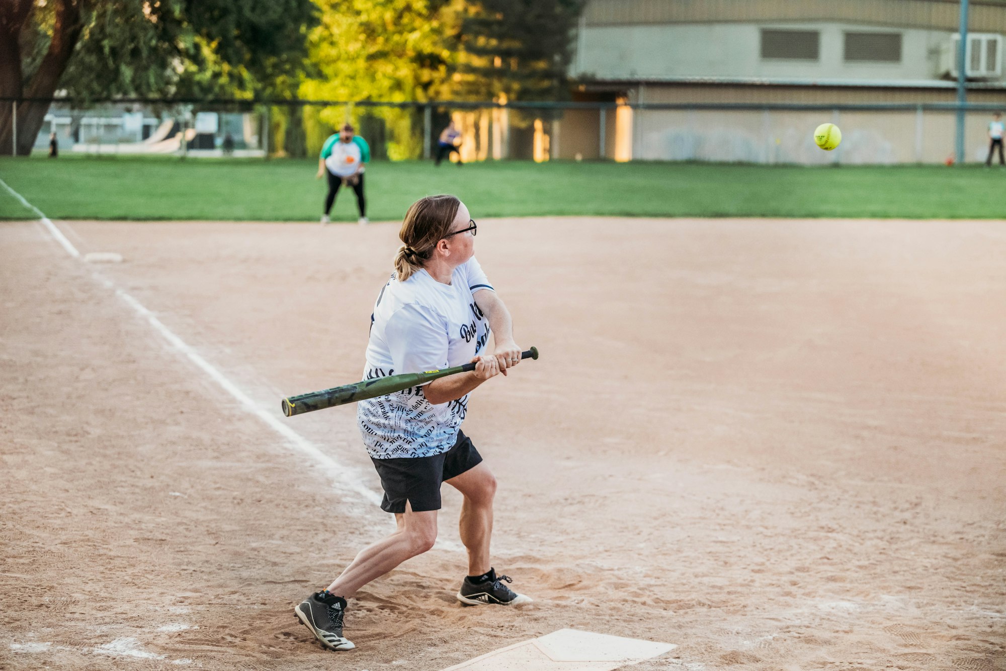 Person playing softball, swinging at a ball.