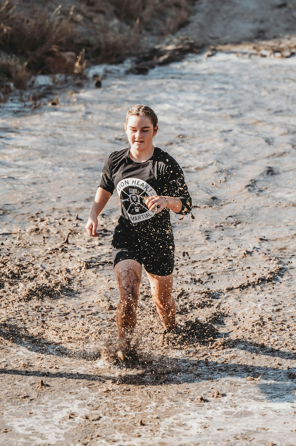A person running through muddy water, splashing around.
