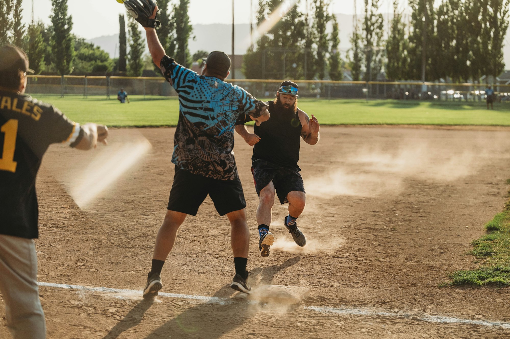 A softball game with a player sliding into home plate as the catcher prepares to tag him. Dust flies, action-packed moment.