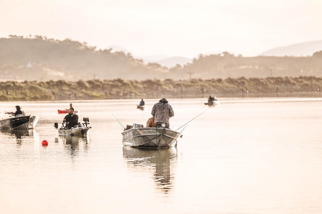 Fishing from boats on a tranquil lake at sunrise or sunset.