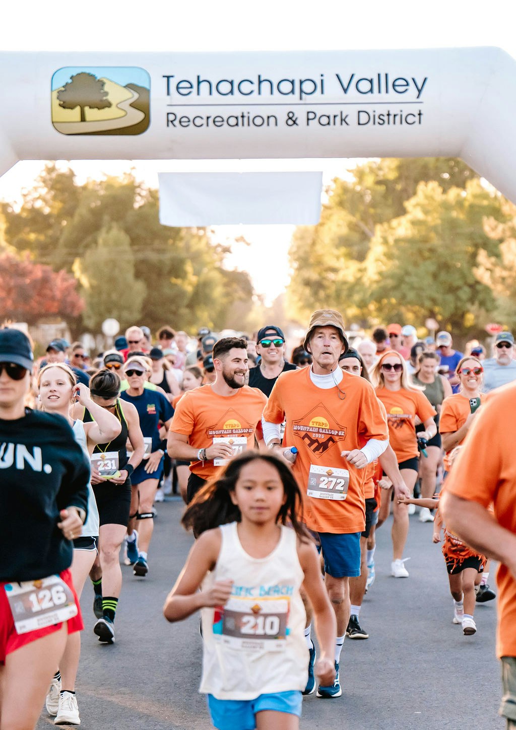 A large group of runners in a race, with a Tehachapi Valley banner above them.