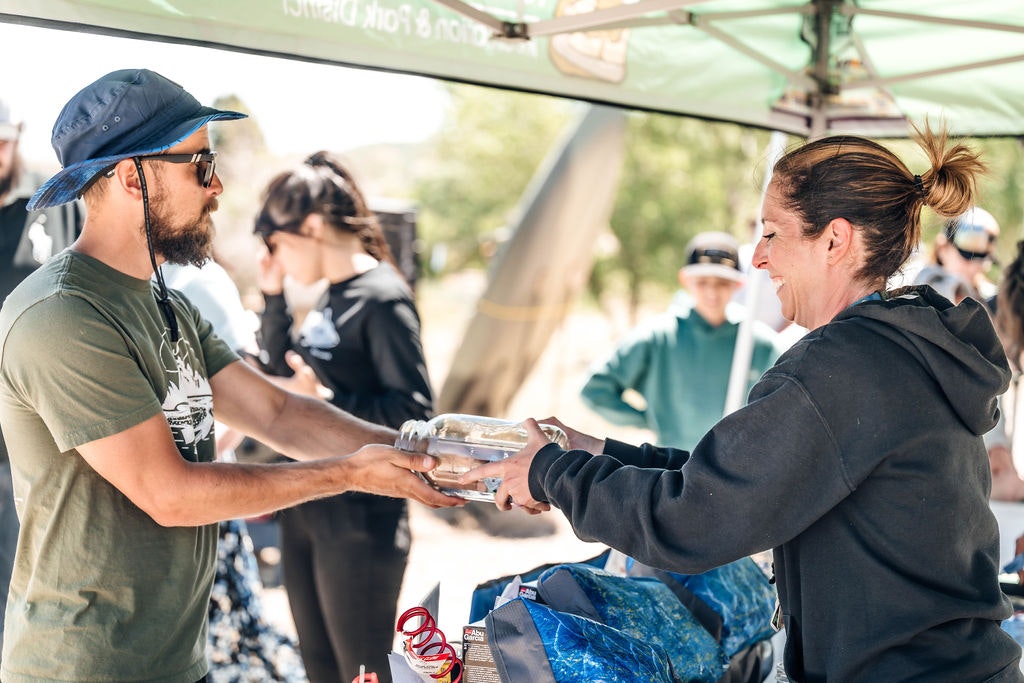 Person handing a meal to another at an outdoor community event.