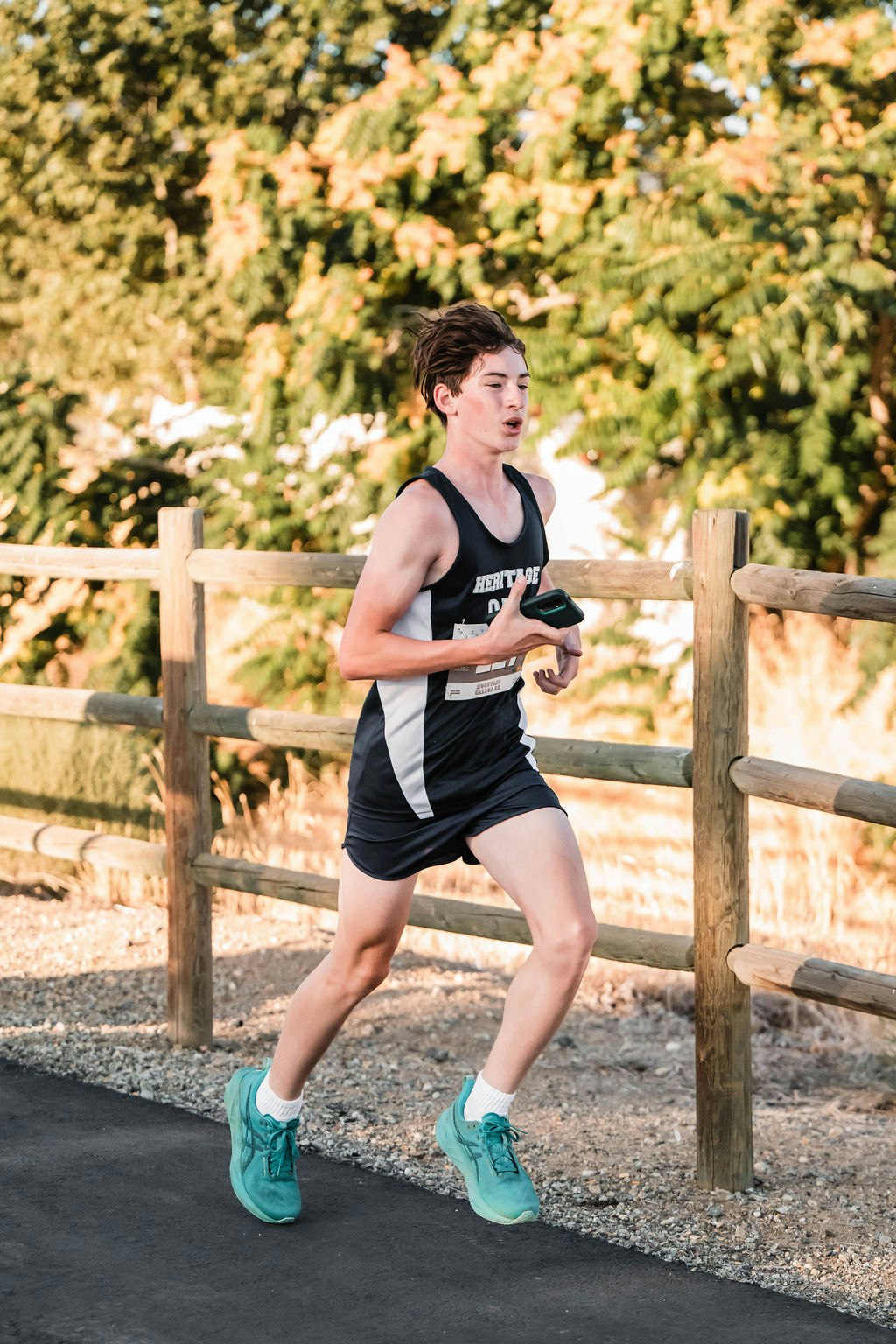 A person running on a path next to a wooden fence, wearing athletic gear.