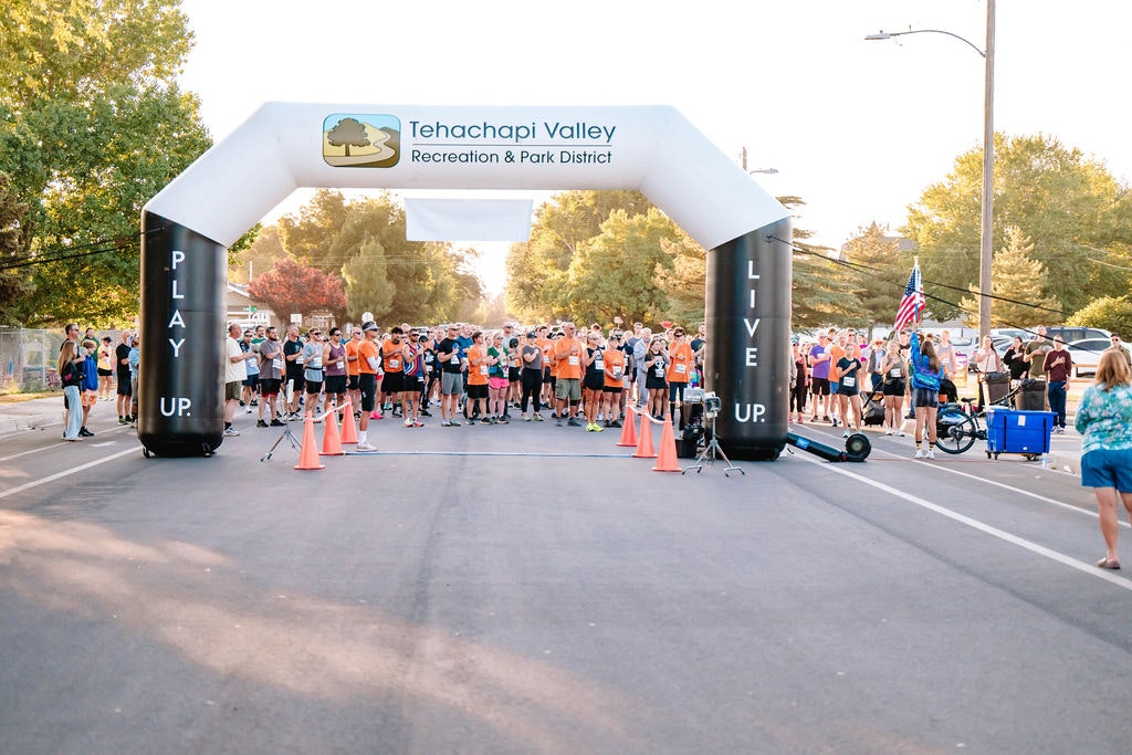 A group of runners at the starting line under an inflatable arch labeled "Tehachapi Valley Recreation & Park District."