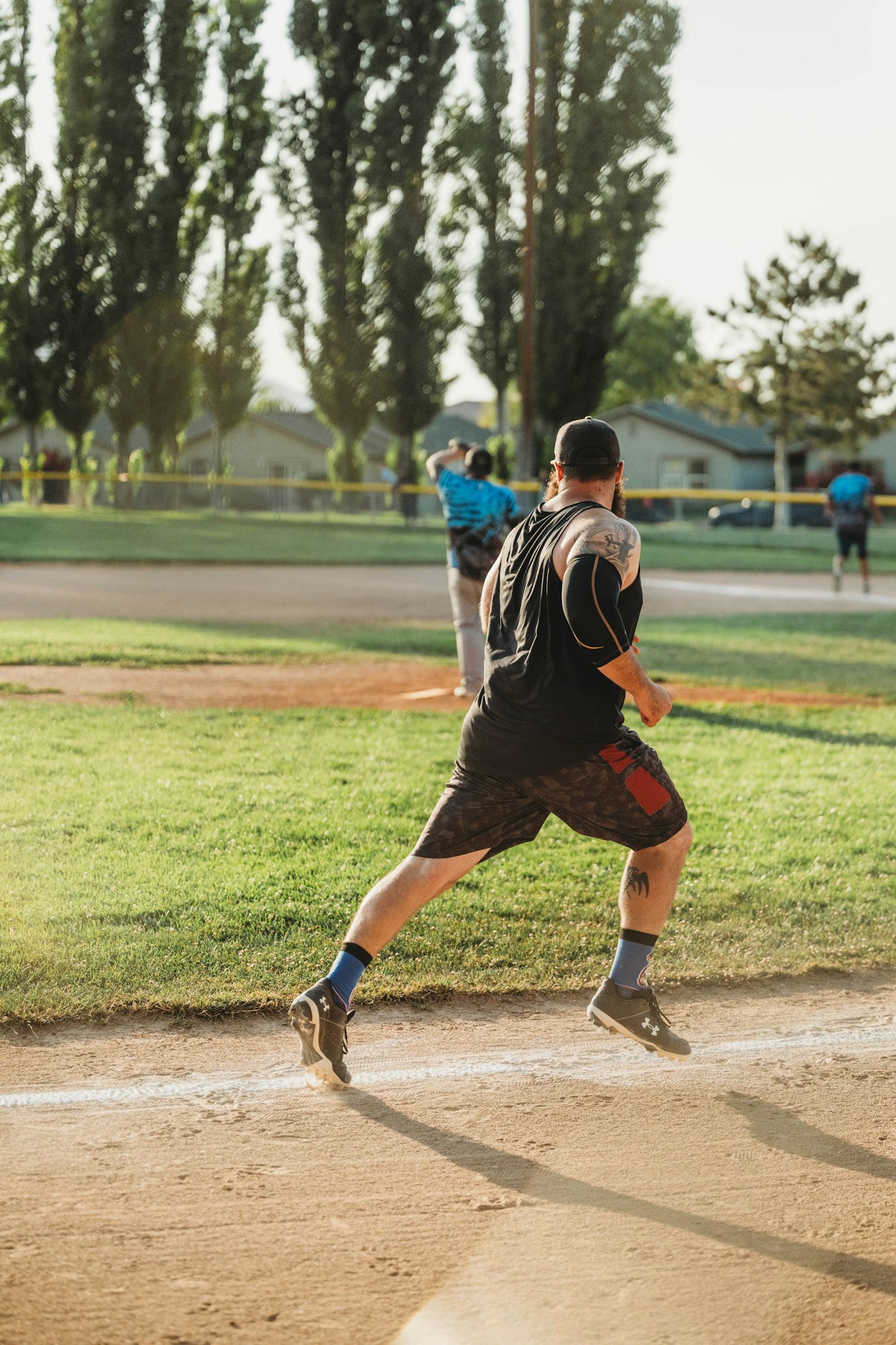 A man running during a softball game on a sunny day.