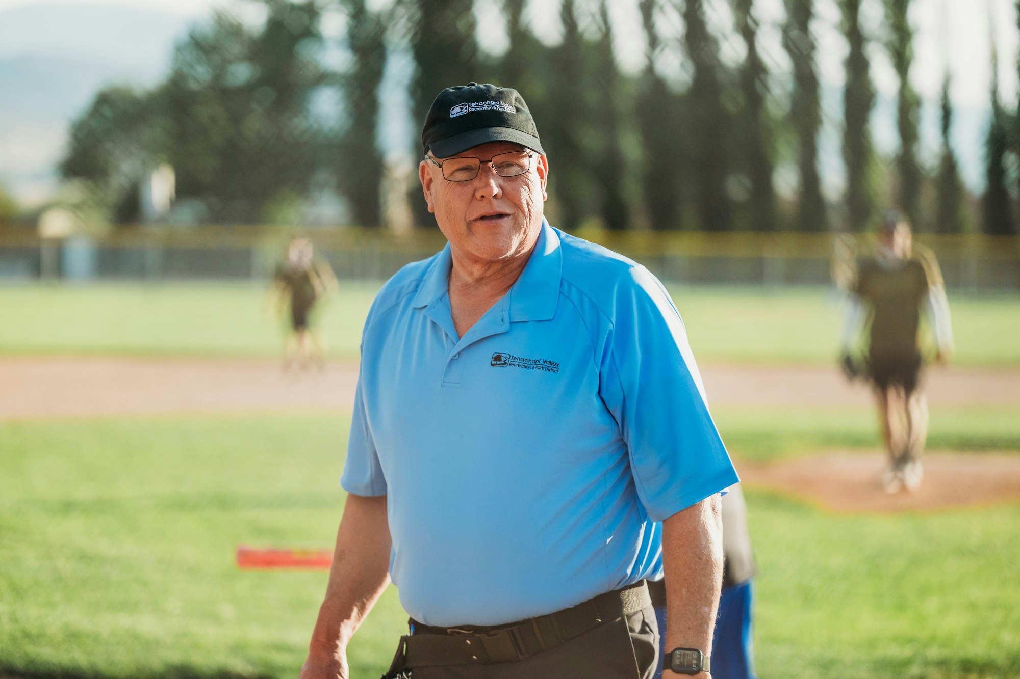 An umpire on a baseball field with players in the background.