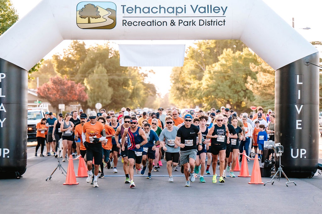A group of runners starting a race under an inflatable arch that says "Tehachapi Valley Recreation & Park District."