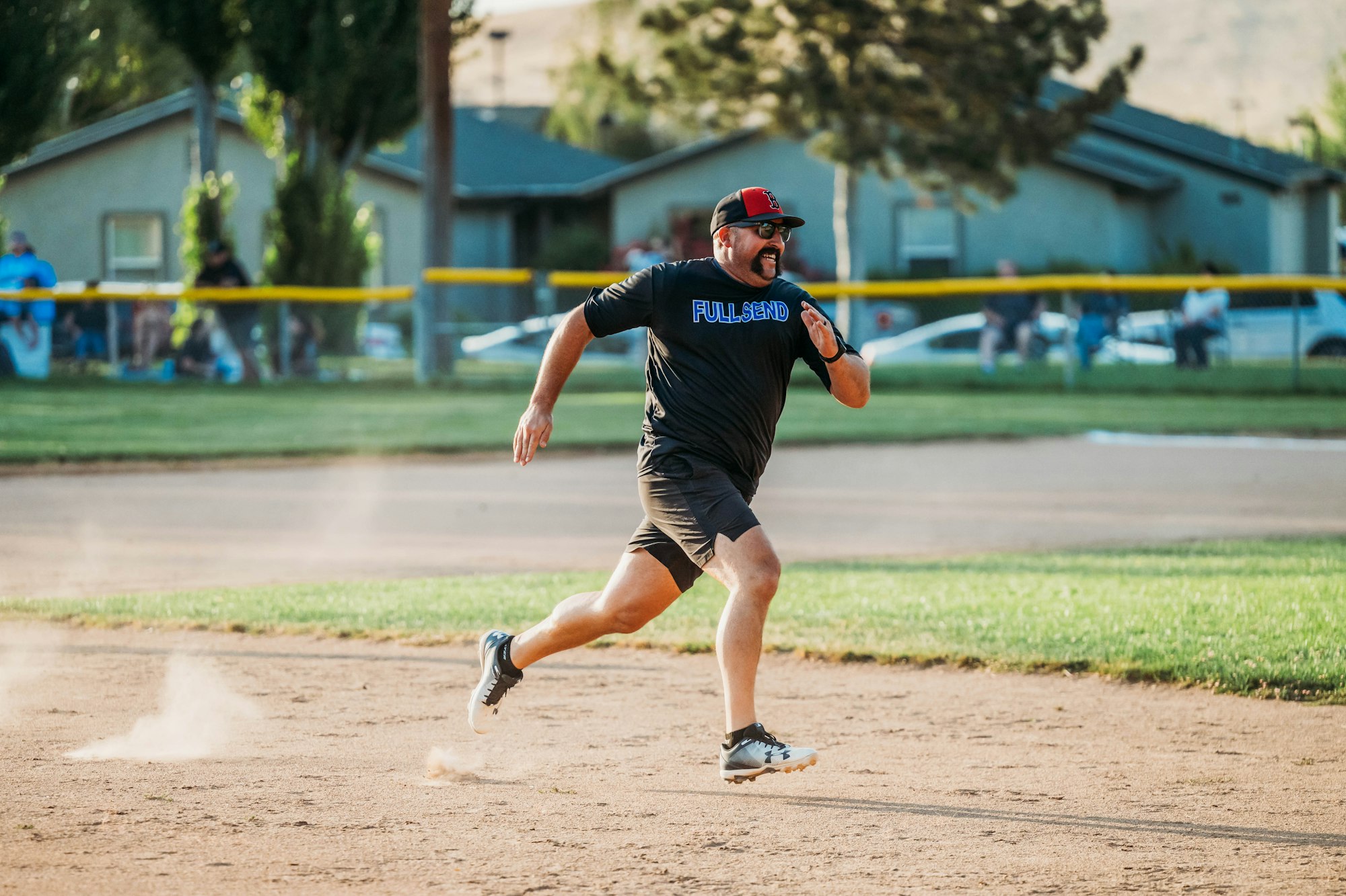 A man running on a dusty baseball field with determination, spectators in the background.