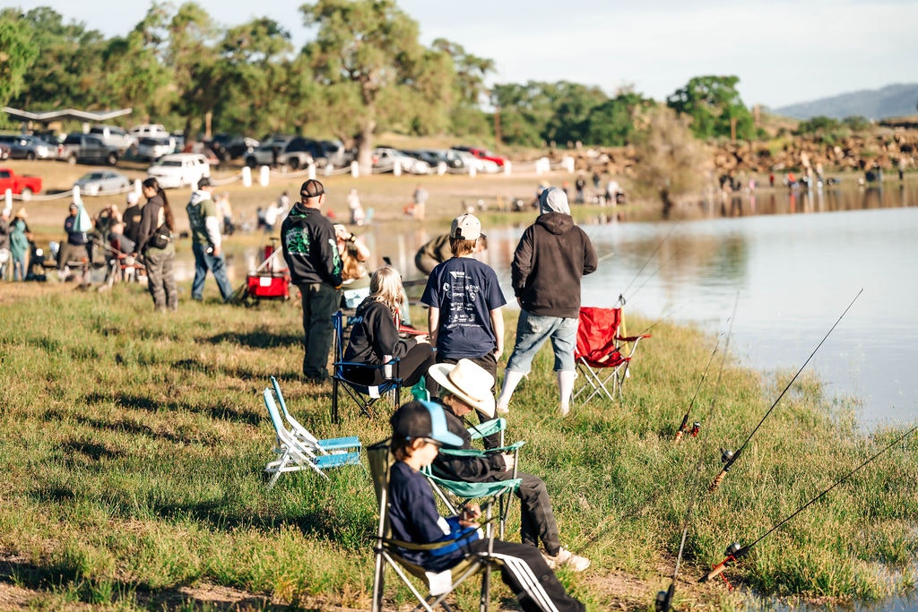 People with fishing rods by a lake, outdoor leisure activity.