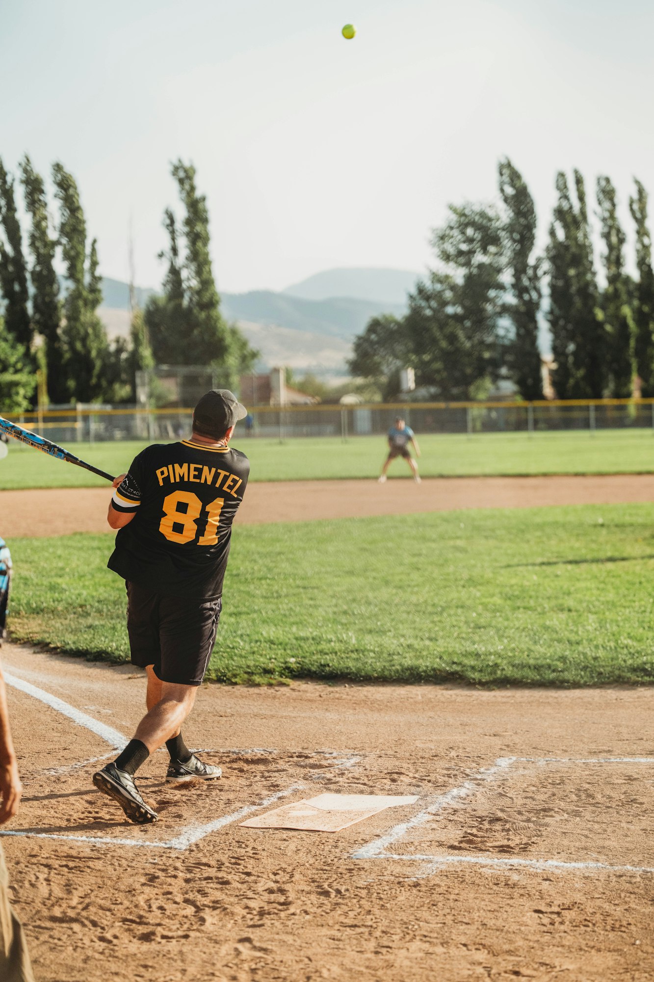 A batter swings at a ball during a baseball game on a sunny day.