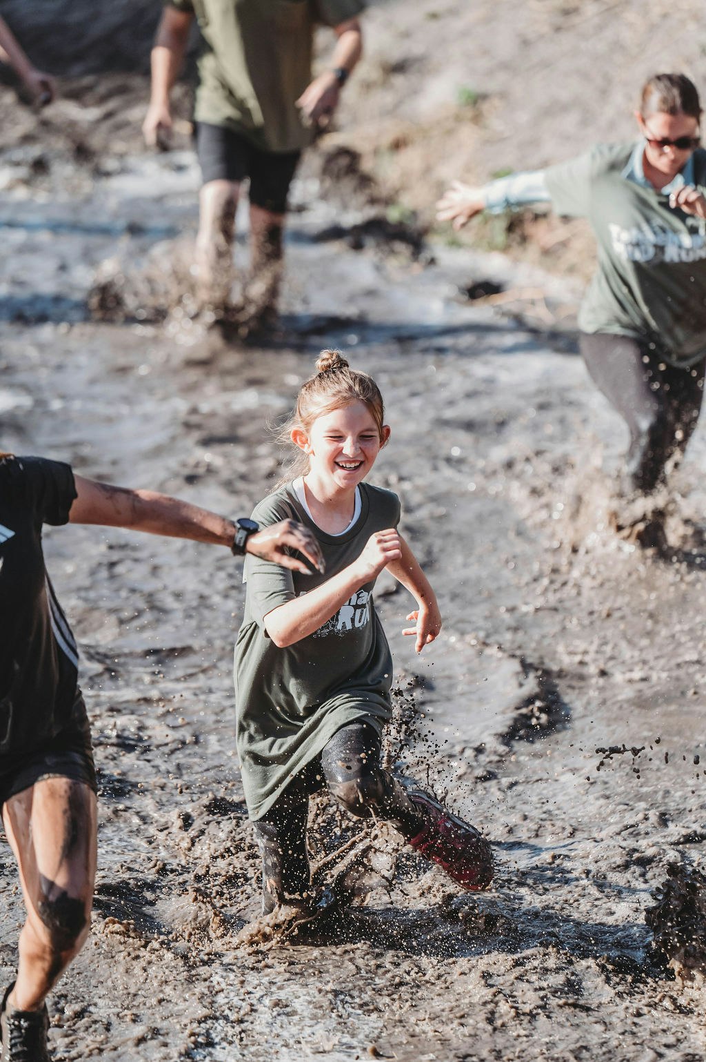 People happily running through a muddy obstacle course.