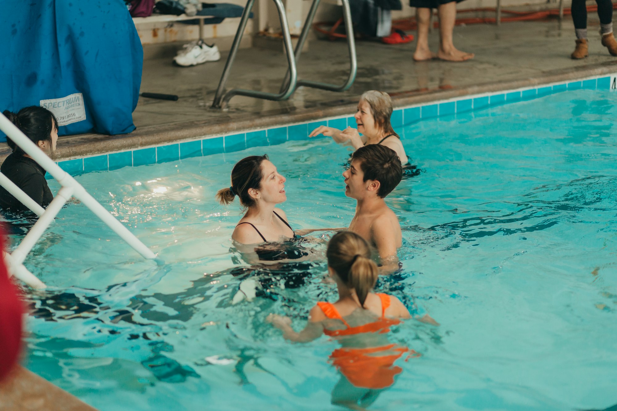 People engaged in a conversation in a swimming pool.