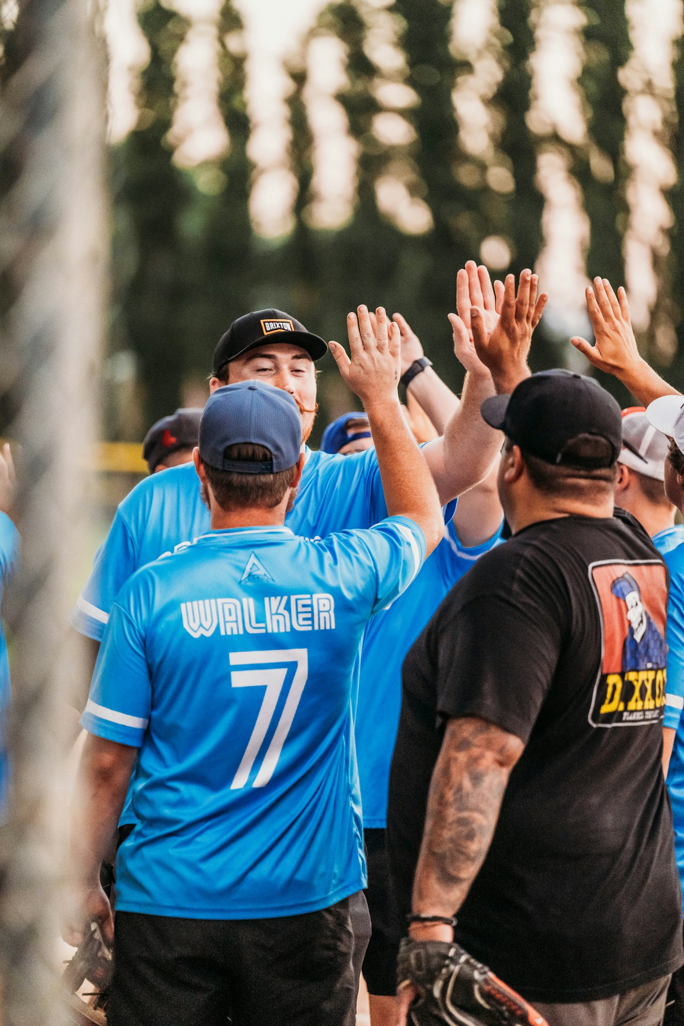 People in blue jerseys high-fiving, suggesting a sports team celebrating or greeting each other.