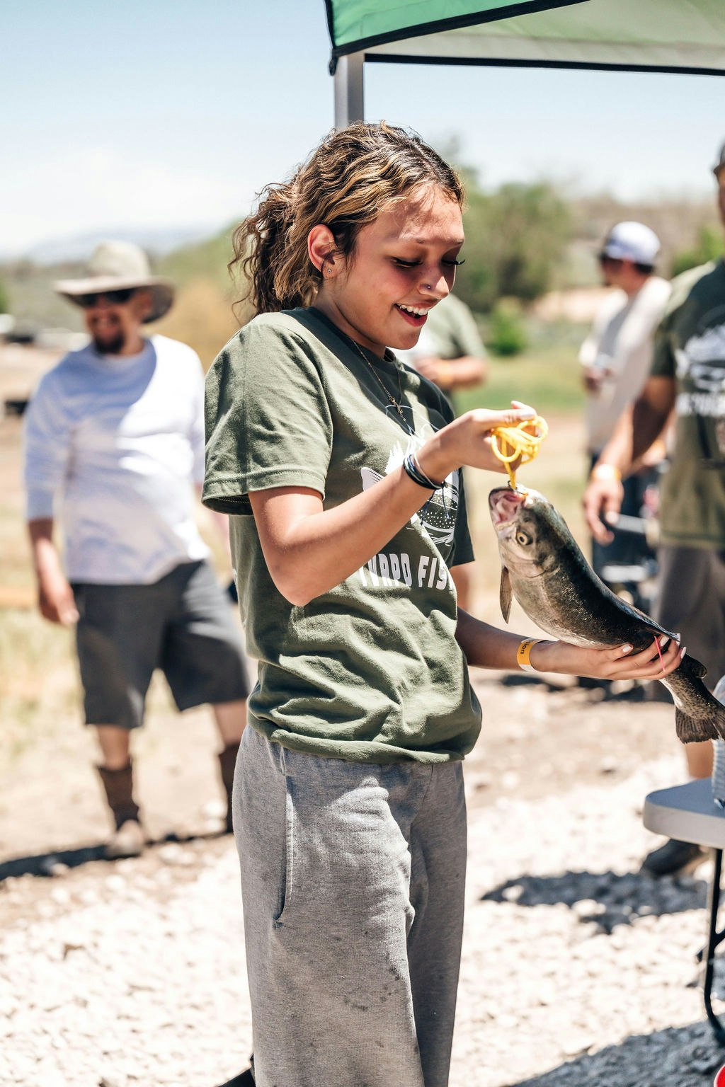 A person holding a fish with others around, likely after a successful fishing trip.