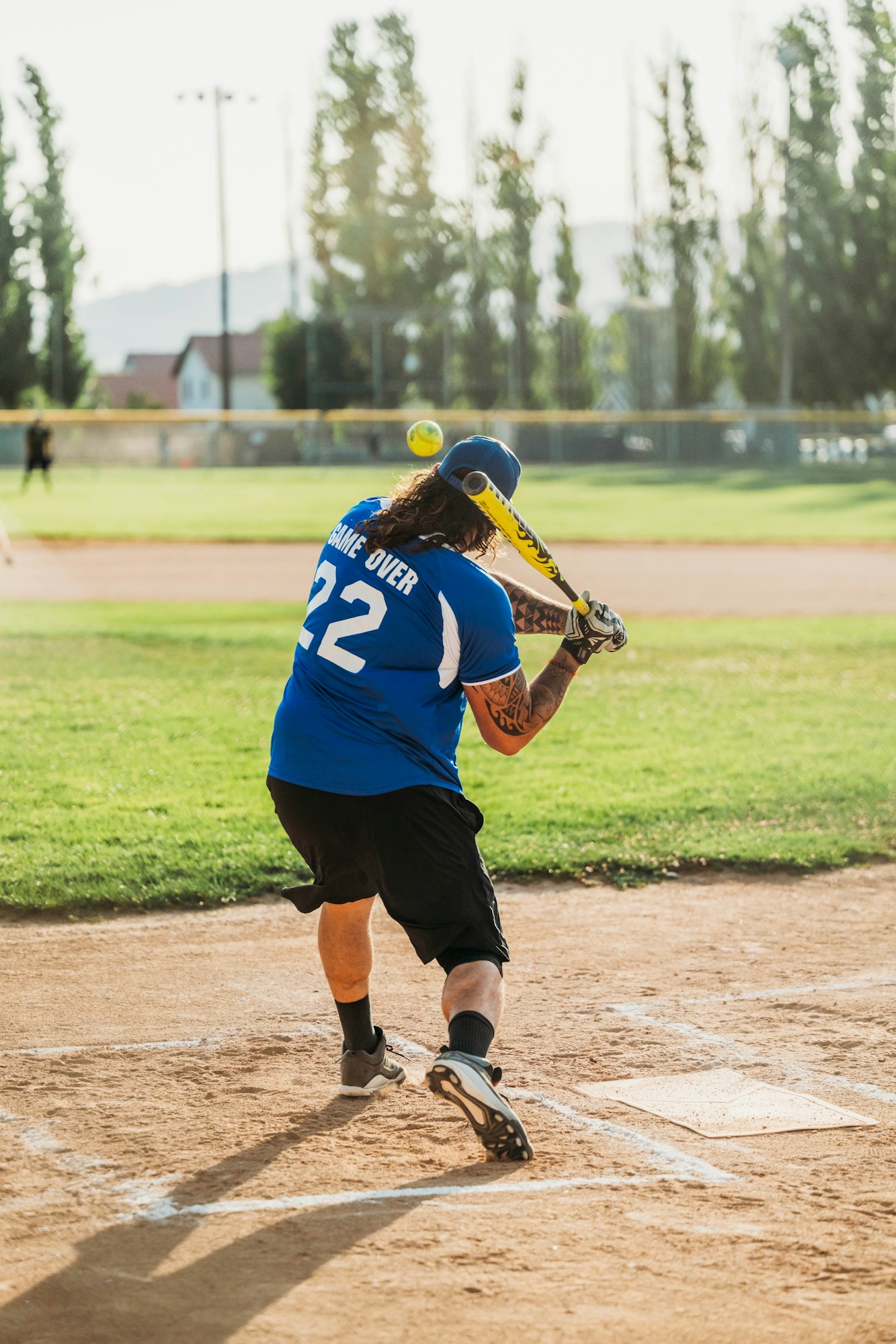 A baseball player swinging at a ball on a sunny day.