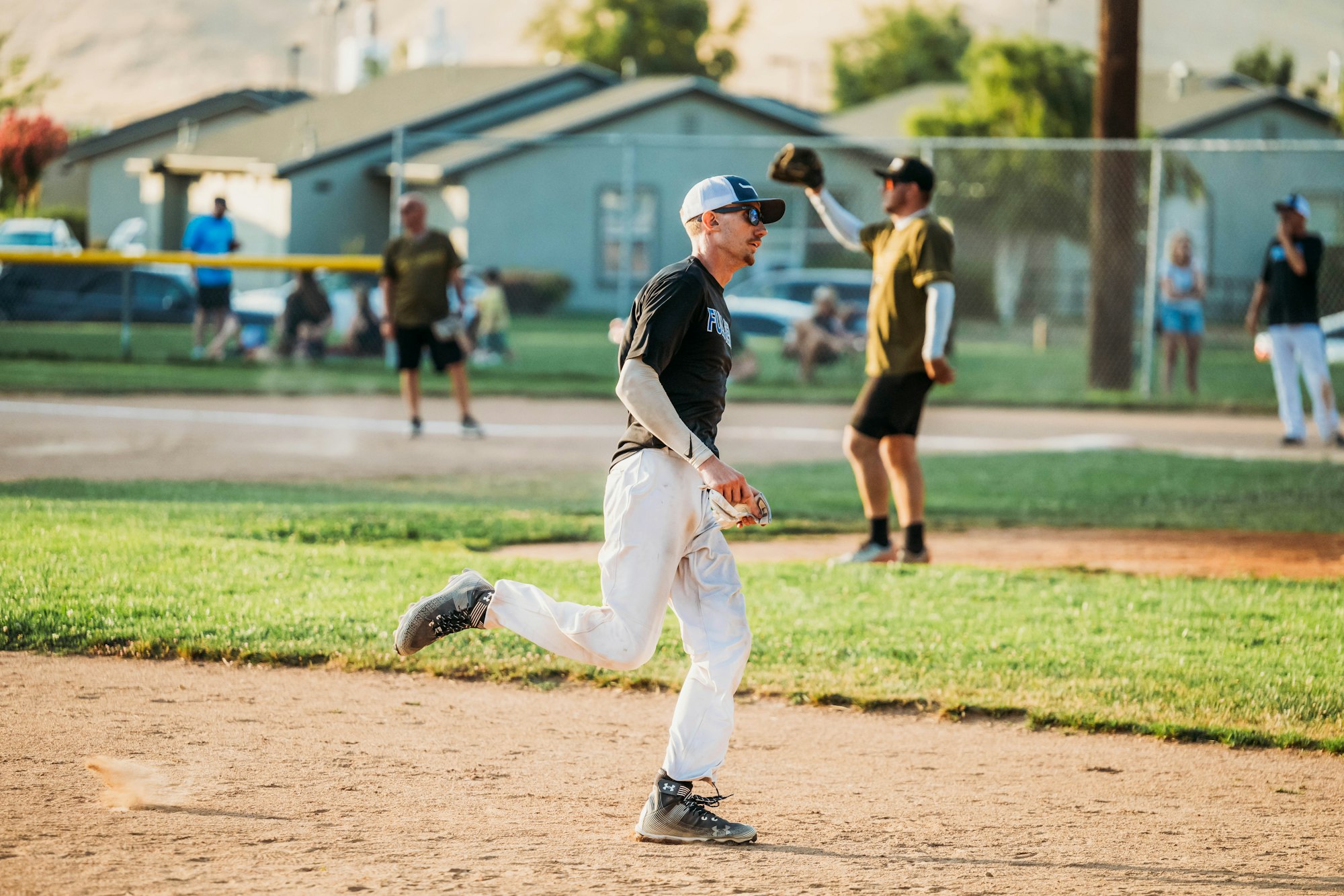 A baseball player walking on the field with others in the background.