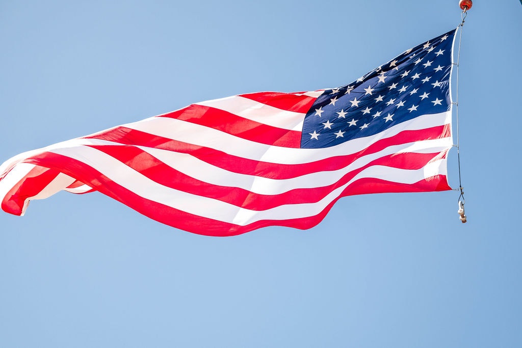An American flag is waving against a clear blue sky.