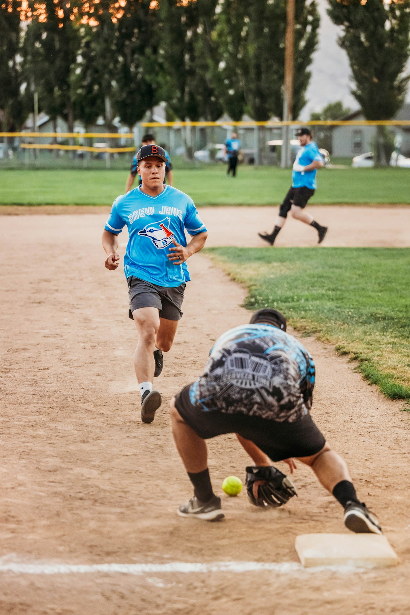 A softball game in progress, with a runner dashing towards a base and a fielder ready to make a play.