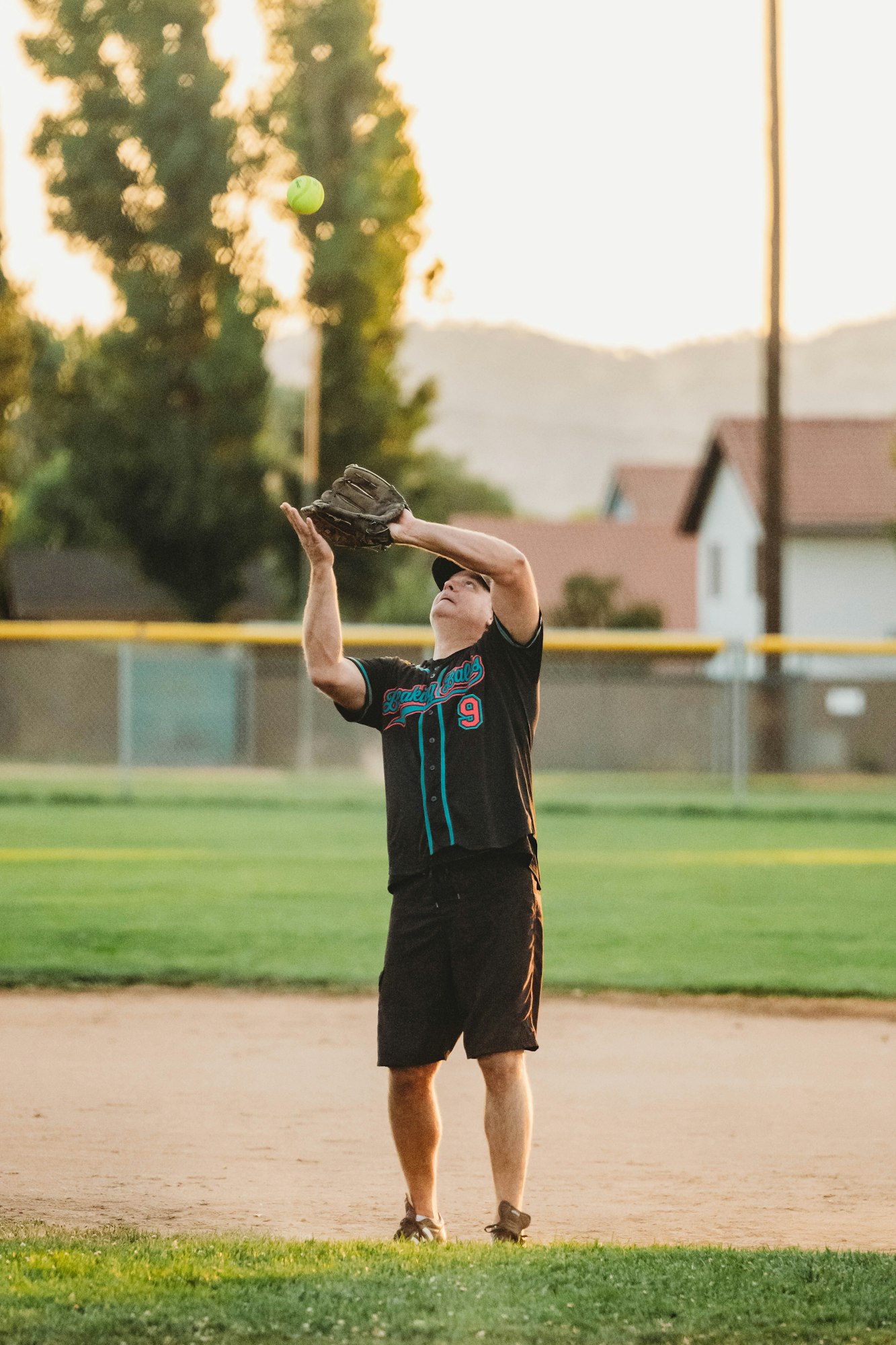 A person catching a ball on a sunny baseball field.
