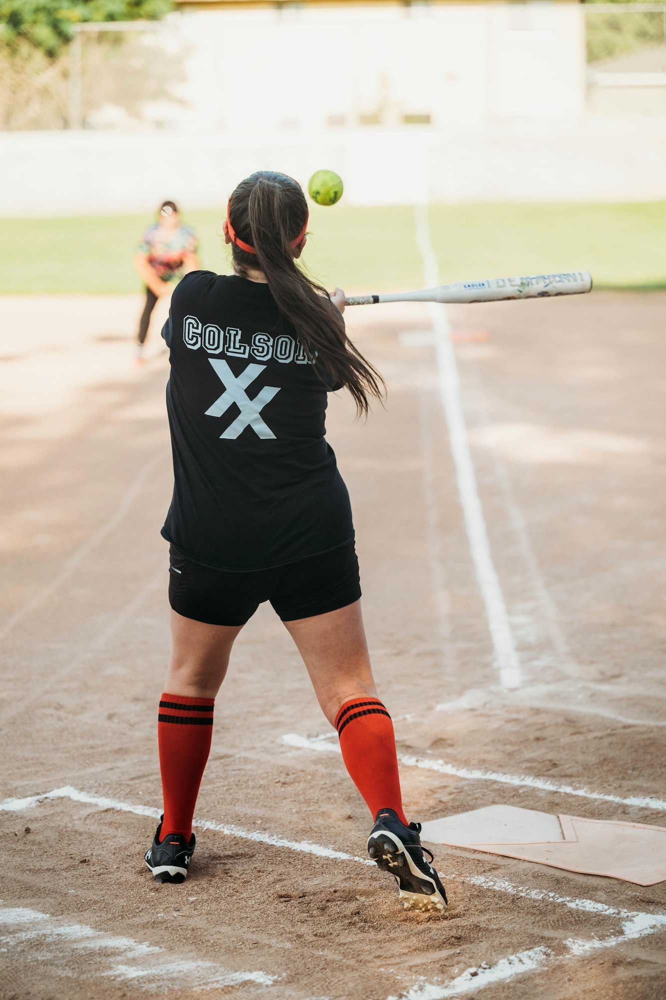 A softball player ready to swing at a pitch, wearing a uniform with "COLSON" on the back.